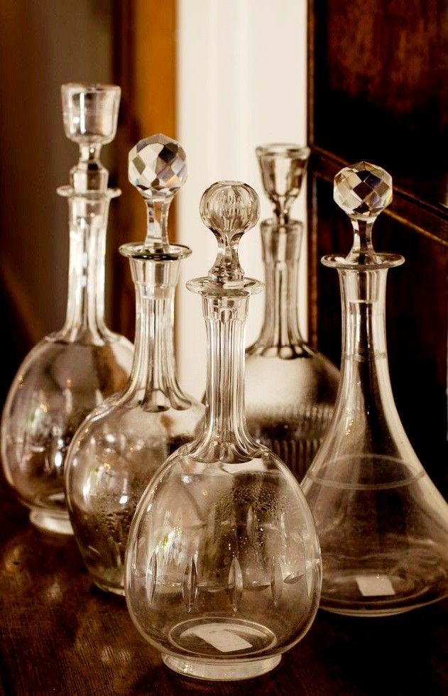 Antique glass decanter collection on polished wood shelf