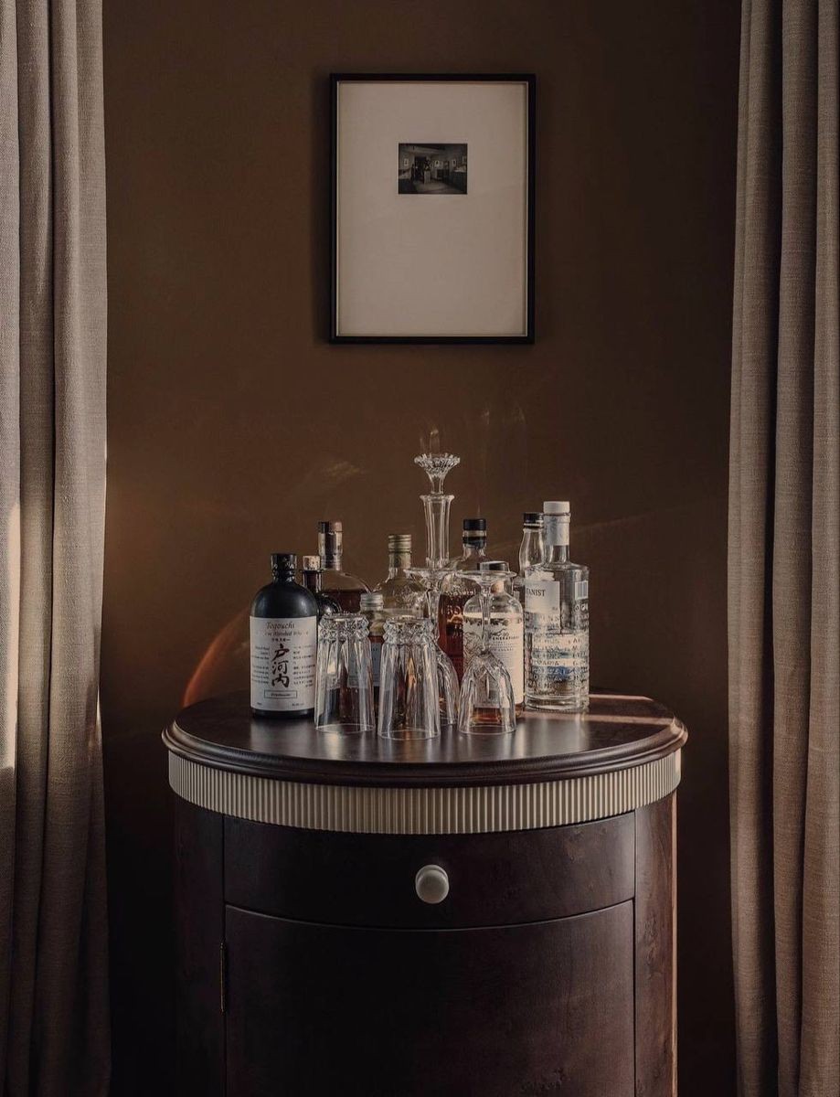 Round drinks cabinet with spirits, linen curtains