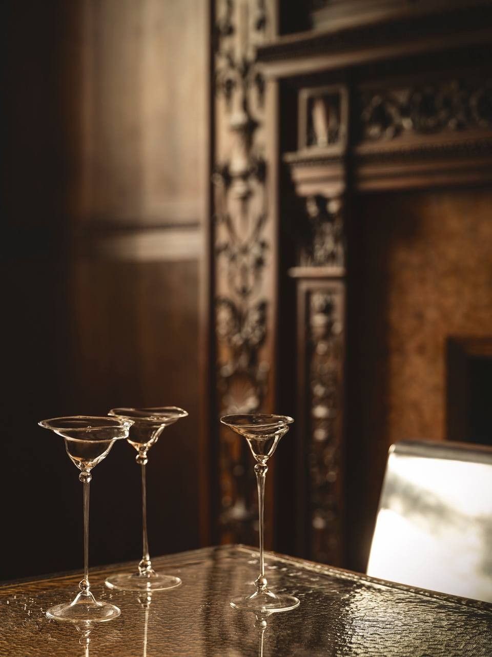 Stemmed glasses before carved wood fireplace mantel