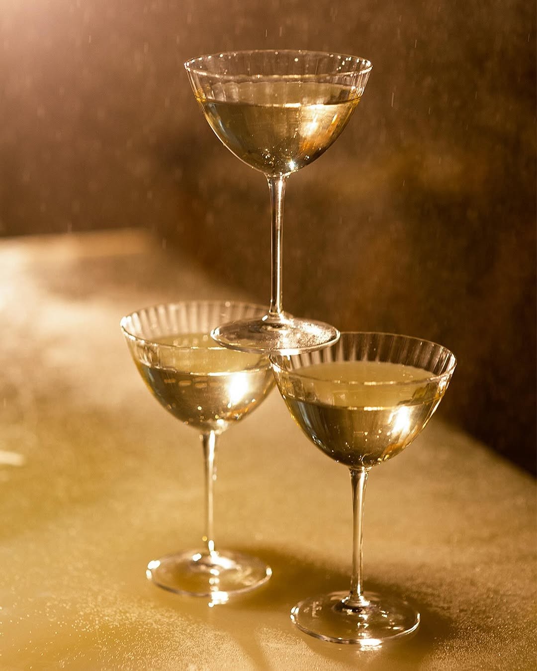 Three coupe glasses in golden editorial light